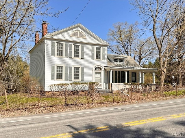 greek revival inspired property with covered porch and a chimney