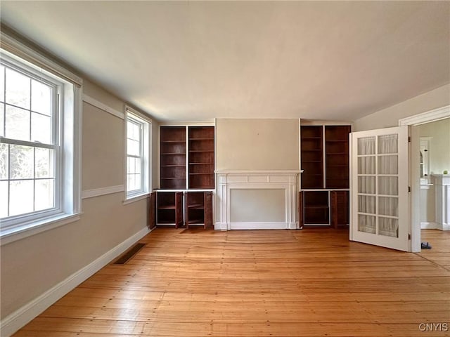 unfurnished living room with baseboards, visible vents, and light wood finished floors