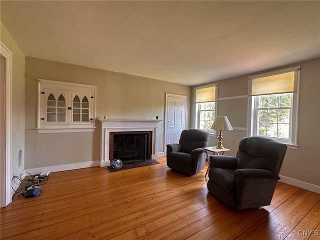 living area featuring baseboards, light wood finished floors, and a fireplace
