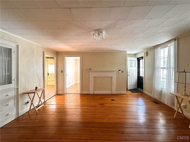 interior space featuring visible vents, hardwood / wood-style floors, ornamental molding, and baseboards