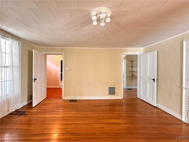 unfurnished room featuring visible vents, wood-type flooring, and crown molding