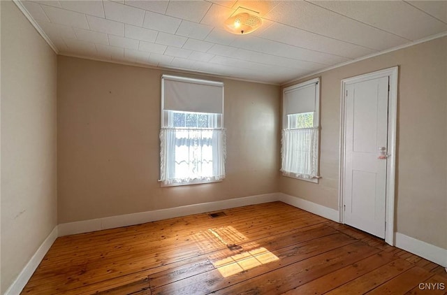 spare room featuring hardwood / wood-style floors, a healthy amount of sunlight, and crown molding
