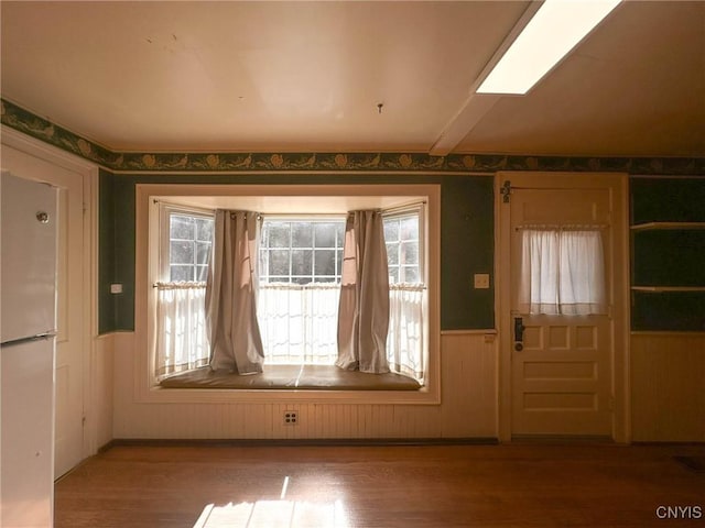doorway to outside with wood finished floors and a wainscoted wall