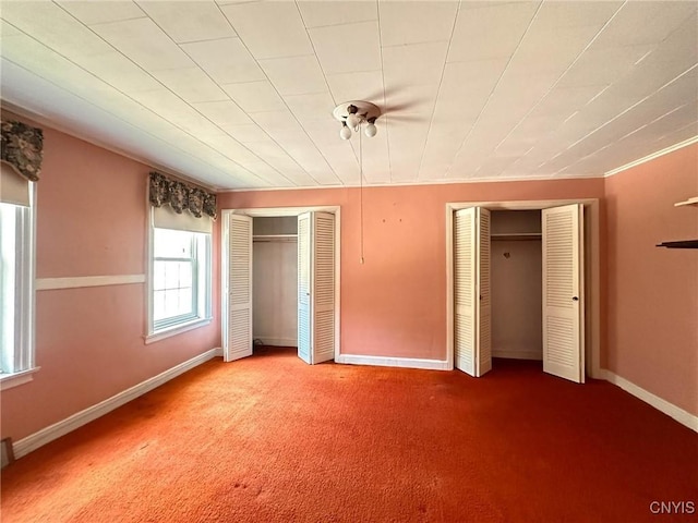 unfurnished bedroom with multiple closets, baseboards, and carpet floors