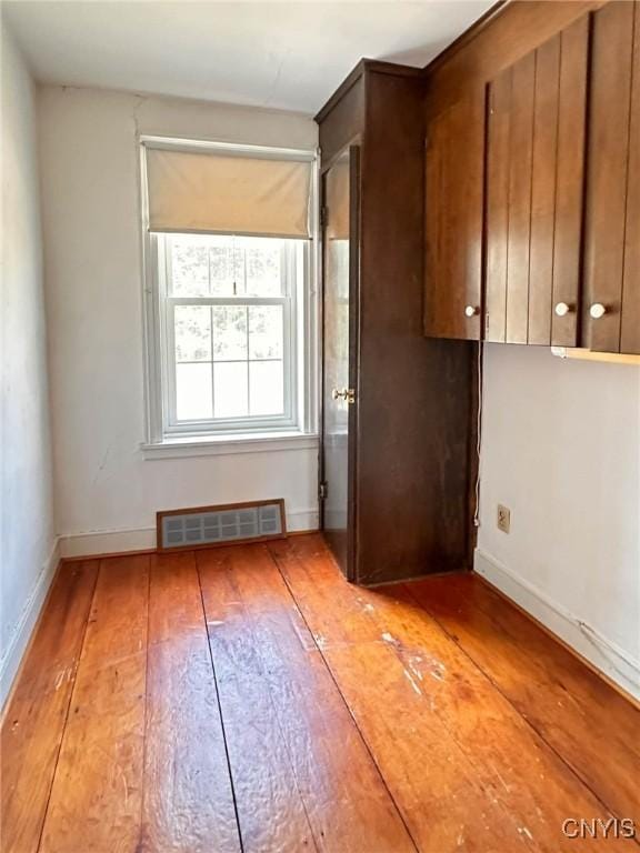unfurnished room with light wood finished floors, visible vents, and baseboards