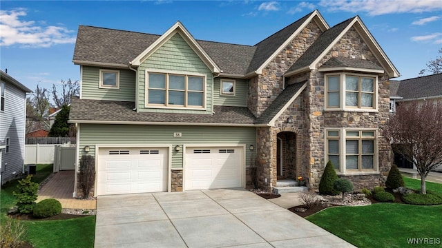 view of front of house featuring fence, a garage, stone siding, roof with shingles, and concrete driveway