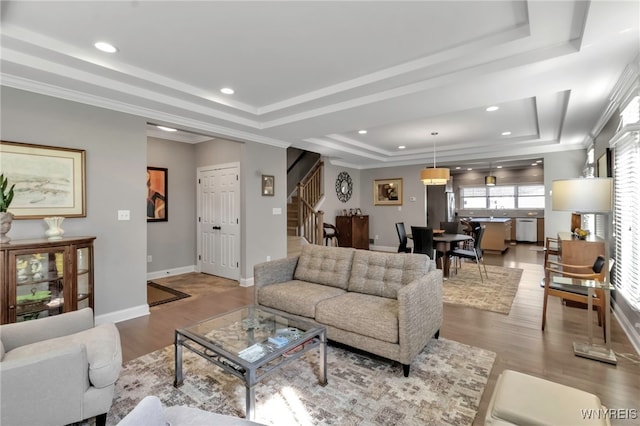 living area with stairway, wood finished floors, recessed lighting, and a tray ceiling