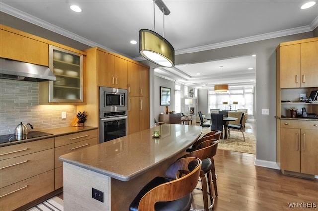 kitchen featuring decorative backsplash, a breakfast bar, appliances with stainless steel finishes, ventilation hood, and dark wood-style floors
