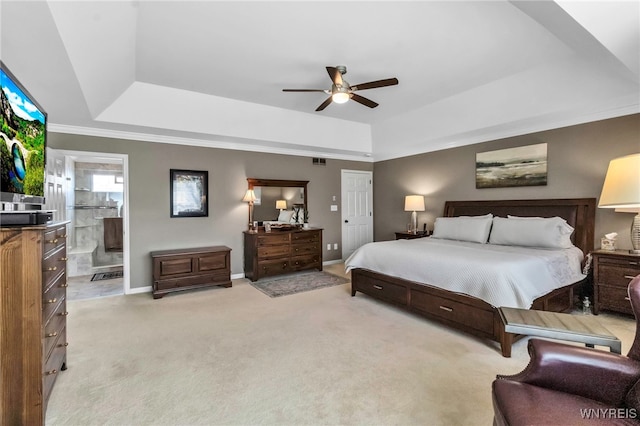 bedroom with ceiling fan, a tray ceiling, light carpet, baseboards, and ensuite bathroom
