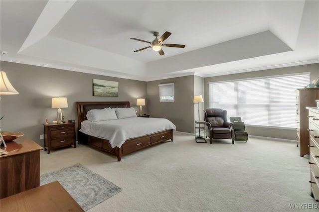 bedroom with baseboards, a ceiling fan, a raised ceiling, and light carpet