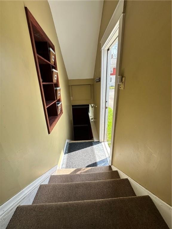 stairs featuring lofted ceiling and baseboards