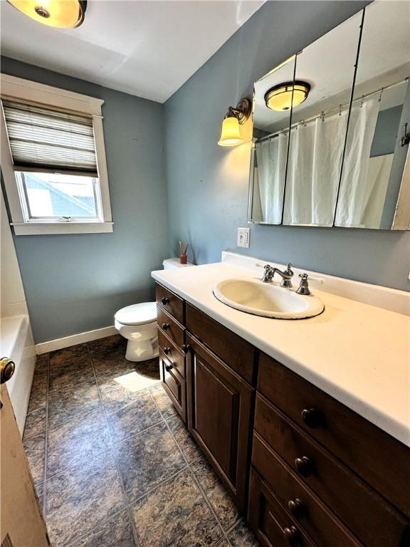 bathroom with toilet, curtained shower, vanity, and baseboards