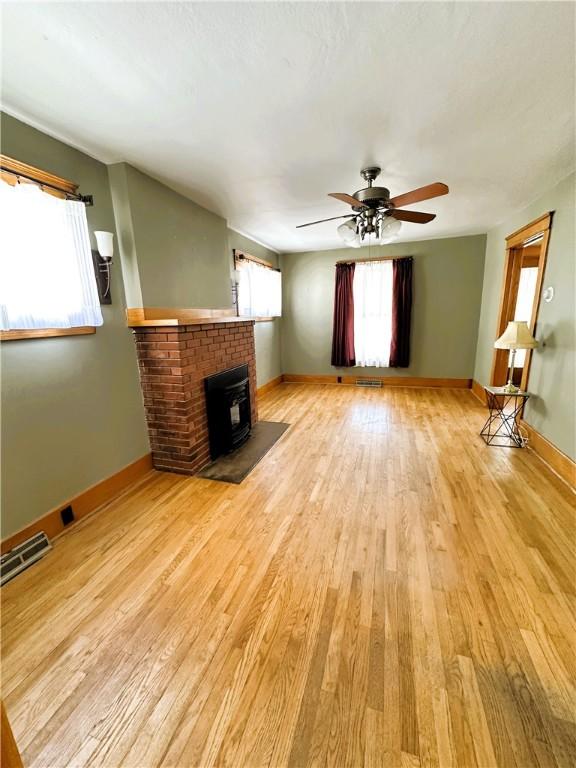 unfurnished living room with baseboards, light wood-type flooring, visible vents, and a ceiling fan