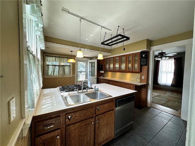 kitchen featuring a sink, glass insert cabinets, rail lighting, hanging light fixtures, and dishwasher