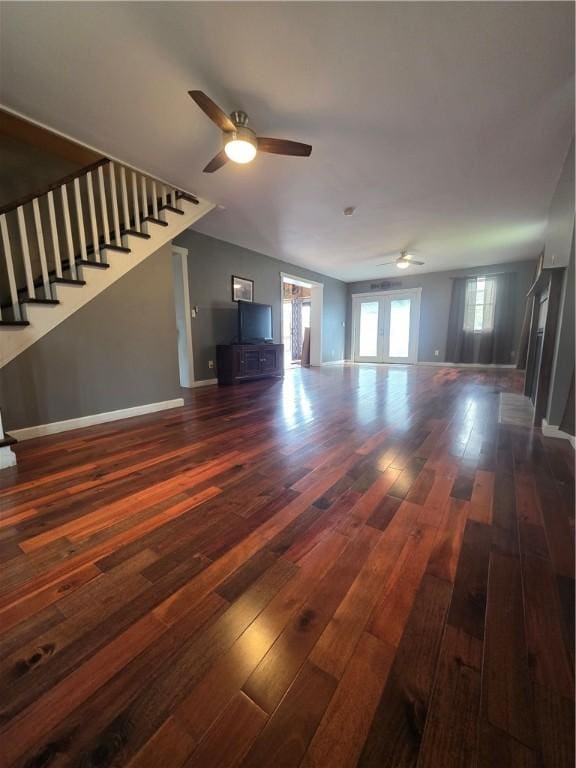 unfurnished living room with a ceiling fan, dark wood-style flooring, stairs, and baseboards