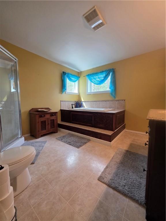 bathroom featuring tile patterned flooring, toilet, visible vents, a stall shower, and a garden tub