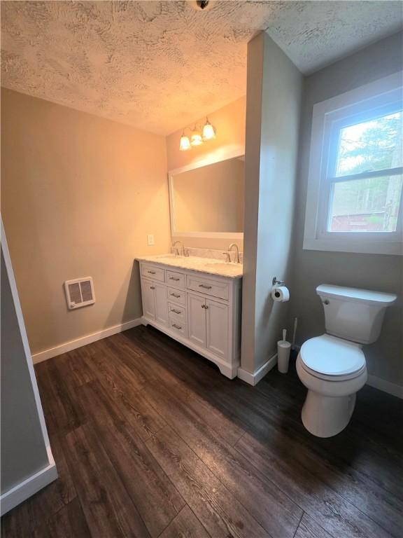 bathroom featuring toilet, a textured ceiling, a sink, and wood finished floors