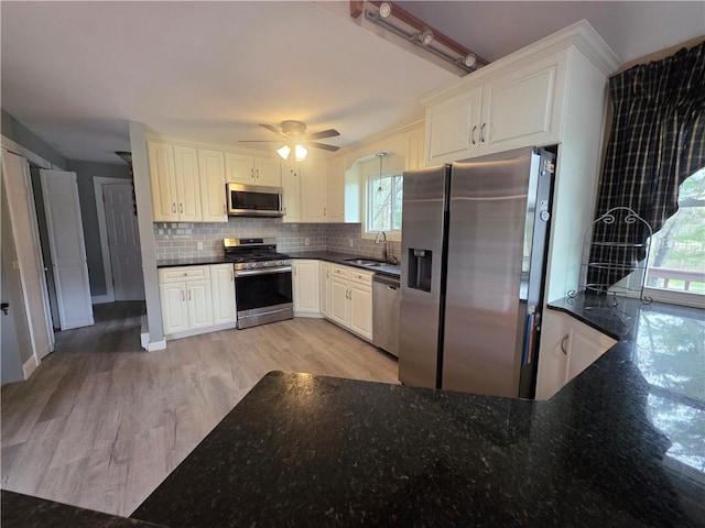 kitchen featuring a sink, ceiling fan, tasteful backsplash, light wood-type flooring, and appliances with stainless steel finishes