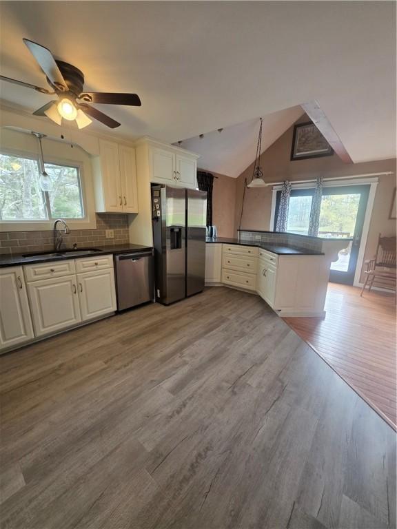 kitchen with light wood-type flooring, dark countertops, appliances with stainless steel finishes, and a sink