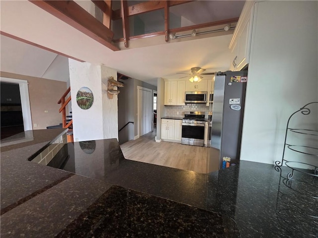 kitchen with dark stone countertops, tasteful backsplash, white cabinets, appliances with stainless steel finishes, and ceiling fan