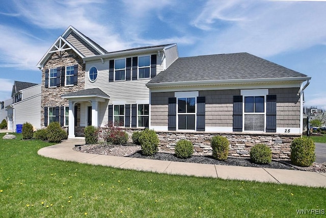 view of front of home with a shingled roof, a front lawn, and stone siding