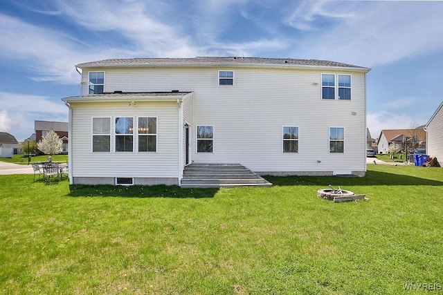 rear view of property with a lawn and a fire pit
