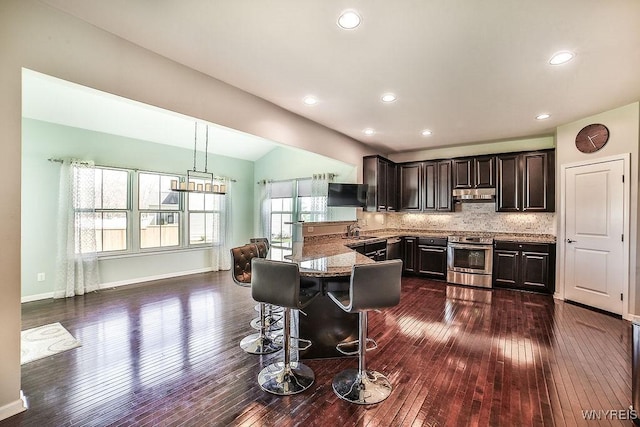 kitchen with dark wood-style flooring, a peninsula, under cabinet range hood, and stainless steel range with electric cooktop