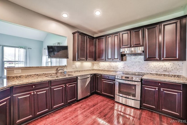 kitchen with light stone countertops, dark brown cabinetry, stainless steel appliances, under cabinet range hood, and dark wood-style floors