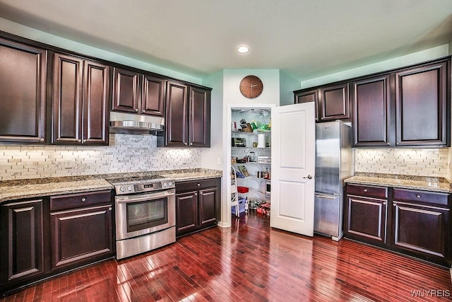 kitchen with light stone countertops, stainless steel appliances, dark wood finished floors, and under cabinet range hood