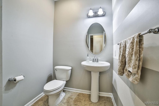 half bathroom with baseboards, tile patterned flooring, and toilet