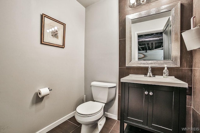 half bathroom with vanity, baseboards, tile patterned flooring, and toilet