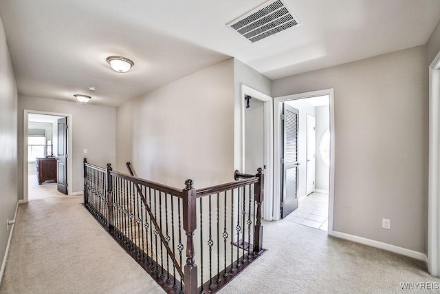 corridor featuring visible vents, carpet, baseboards, and an upstairs landing