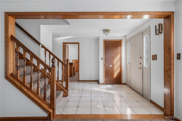 foyer entrance with stairs and baseboards