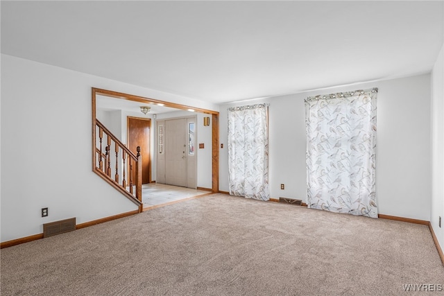 unfurnished room with stairway, visible vents, baseboards, and carpet floors