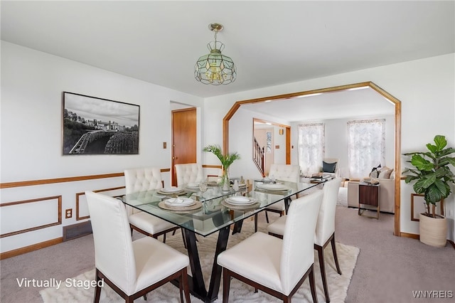 dining room with light colored carpet, stairs, and baseboards