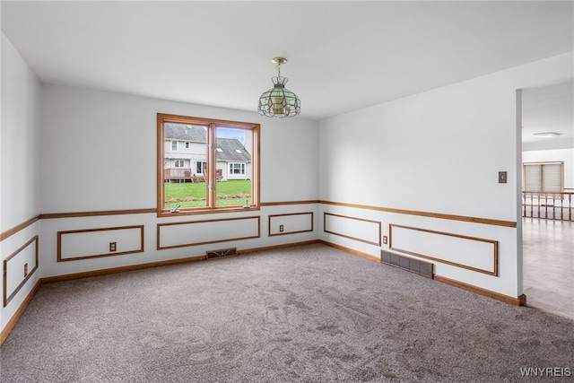carpeted spare room with visible vents and baseboards