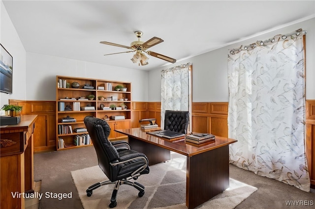 carpeted office with ceiling fan and wainscoting