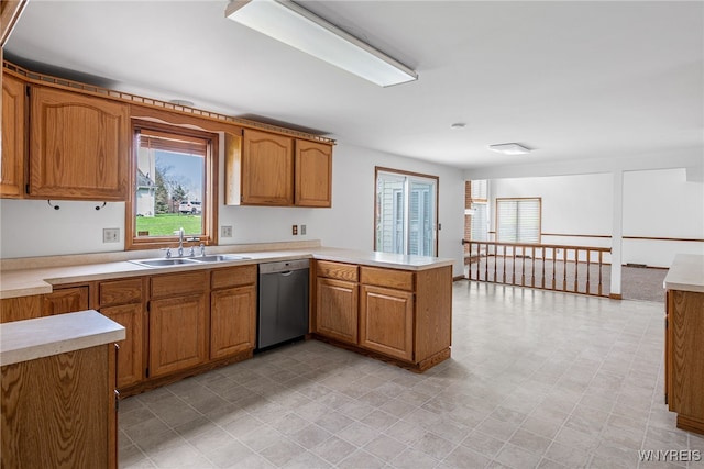 kitchen featuring light countertops, a peninsula, dishwasher, and a sink