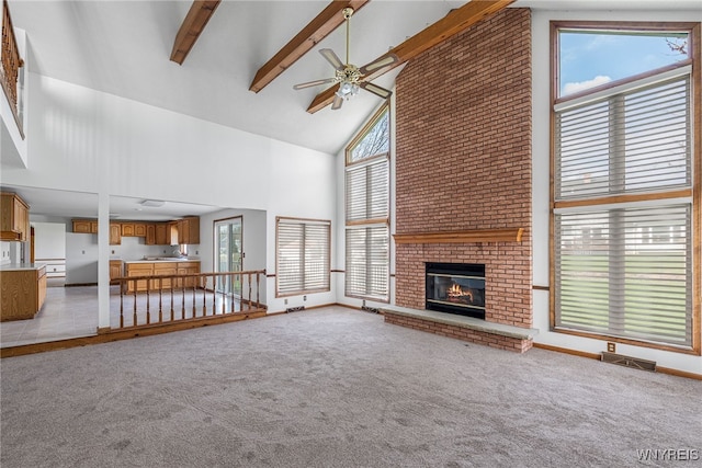 unfurnished living room with ceiling fan, a healthy amount of sunlight, high vaulted ceiling, and light carpet