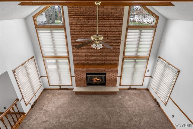 unfurnished living room with a brick fireplace, a textured ceiling, ceiling fan, and carpet floors