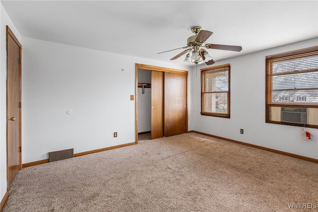 unfurnished bedroom with visible vents, cooling unit, a closet, and carpet