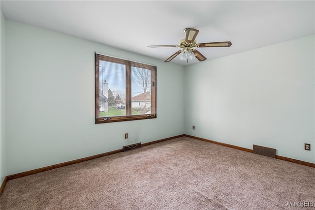 carpeted spare room featuring visible vents, ceiling fan, and baseboards