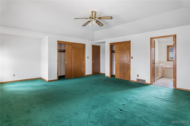 unfurnished bedroom featuring light colored carpet, visible vents, multiple closets, and baseboards
