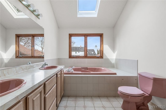 full bath with a skylight, tile patterned floors, a wealth of natural light, toilet, and a sink
