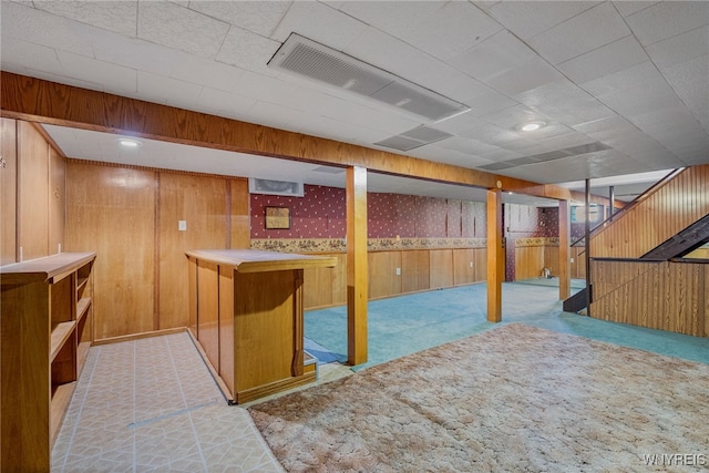finished basement with carpet flooring, visible vents, a bar, wallpapered walls, and wooden walls