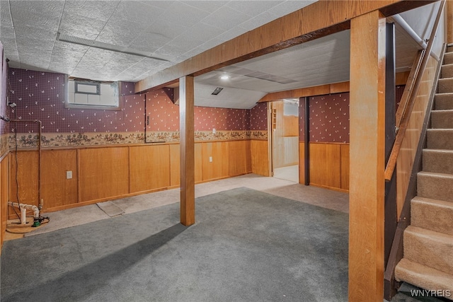 basement featuring wainscoting, stairs, wood walls, and carpet