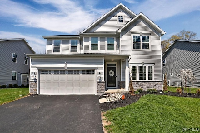 craftsman house with a front yard, driveway, stone siding, and a garage