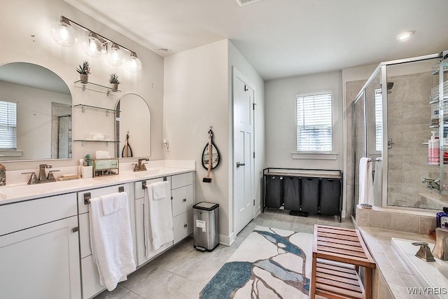 full bath featuring double vanity, a bathtub, a stall shower, and a sink