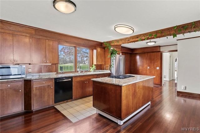 kitchen with brown cabinetry, stainless steel appliances, dark wood finished floors, and a sink