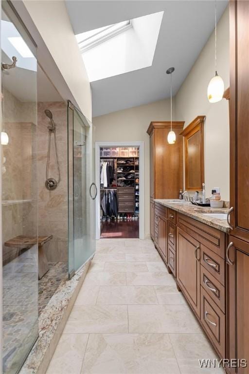 bathroom with a walk in closet, a shower stall, vaulted ceiling with skylight, and vanity
